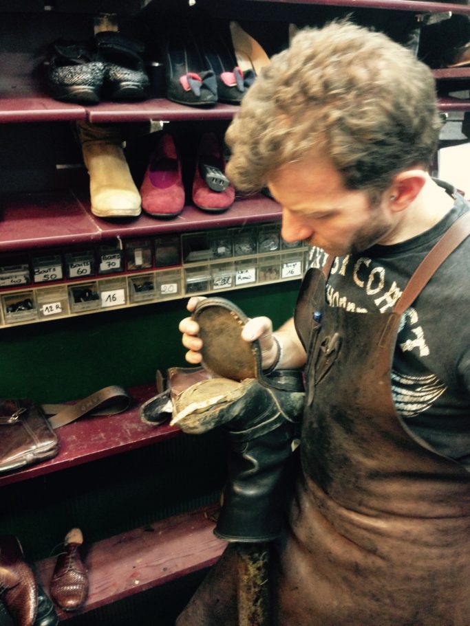 Les débuts du Louis XV dans la boutique des trois journées Artisan cordonnier examinant une chaussure dans son atelier historique à Perpignan.